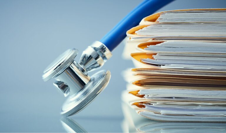 a blue stethoscope draped over a stack of medical folders